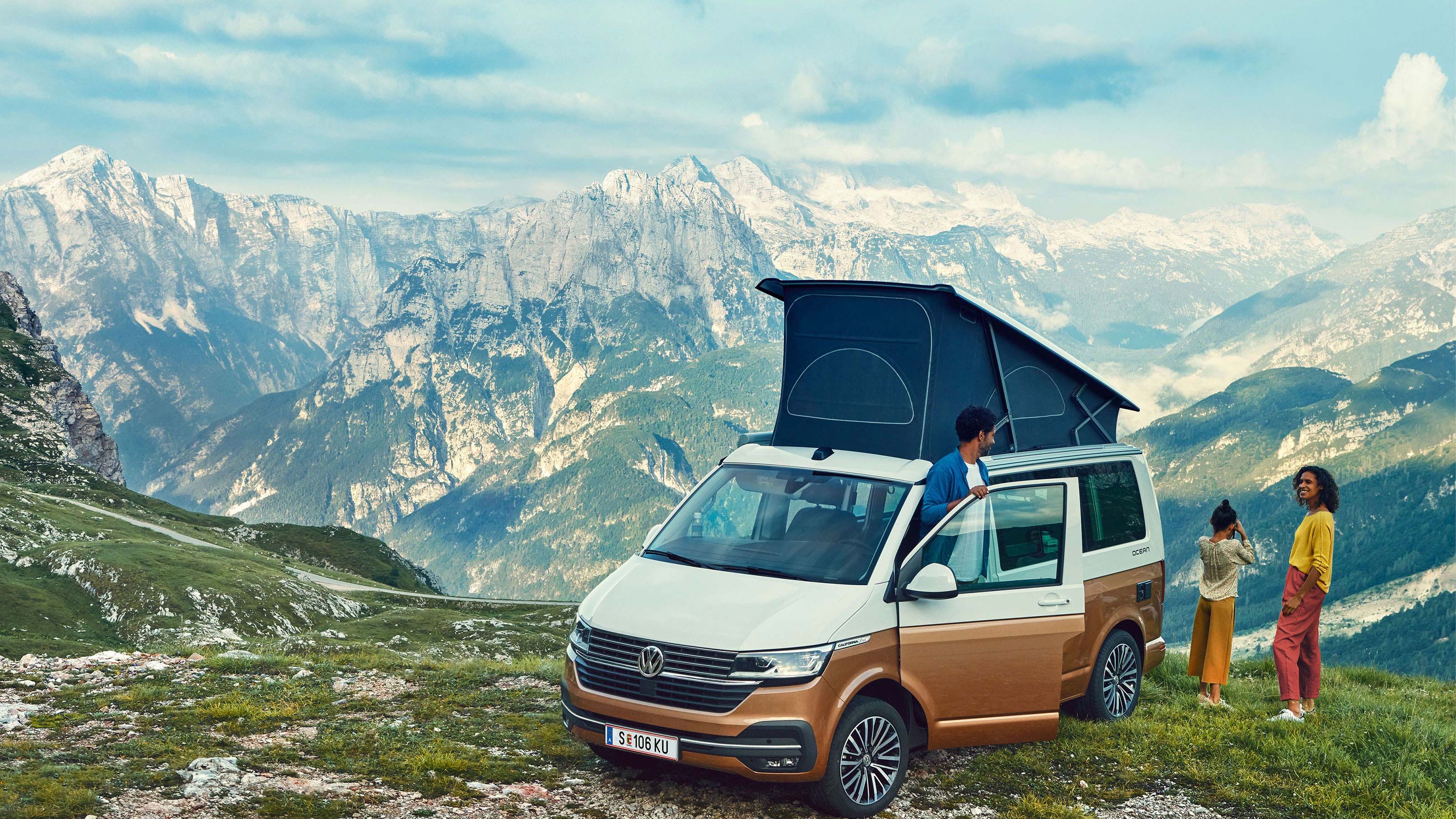 VW California është në lëndinë. Në sfond mund të shihet një vargmal.